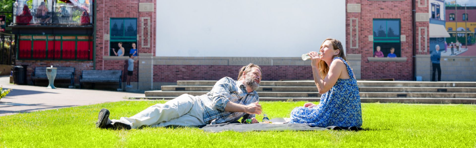a couple sitting on the grass enjoying a picnic